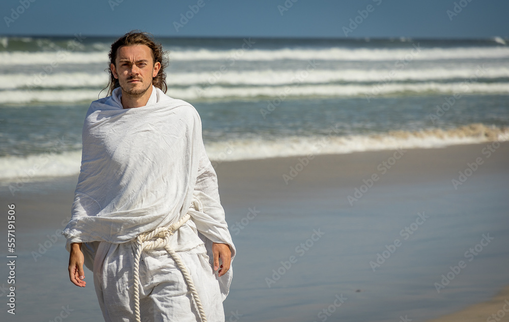 holy, Jesus-type person walking next to sea in white robe