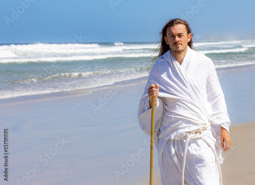 Obraz na płótnie Man in white robe walks near sea with a staff w salonie