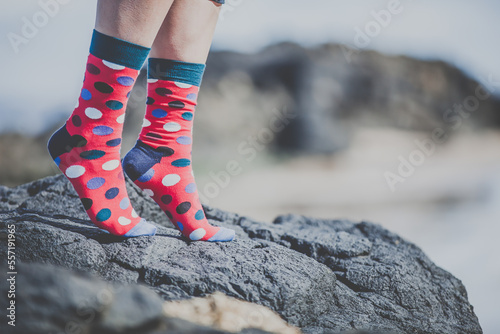 Fototapeta Naklejka Na Ścianę i Meble -  feet of a woman girl in red socks with dots on it standing on a rock at a sandy beach