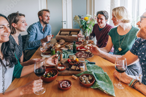 Obraz na plátne friends sitting around the table eating home delivered tapas food
