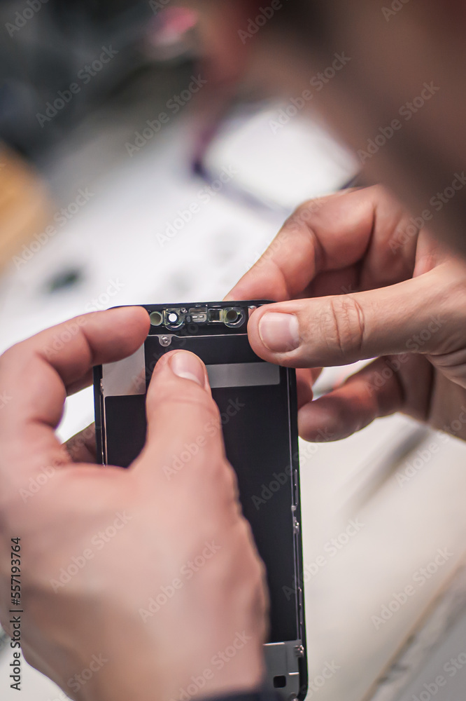 In the electronics repair shop, the master repairs, cleans, controls, arranges the smartphone. Uses equipment and tools for work. Workplace top view, close-up. In the electronics repair shop, the master repairs, cleans, controls, arranges the smartphone. Uses equipment and tools for work. Workplace top view, close-up.