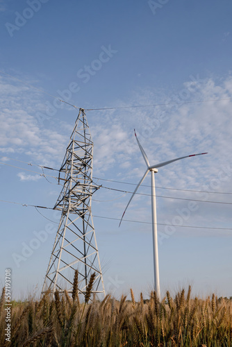 Power transmission line works from windmill energy. Ecofriendly wind turbine produces renewable energy for supporting transmission line tower