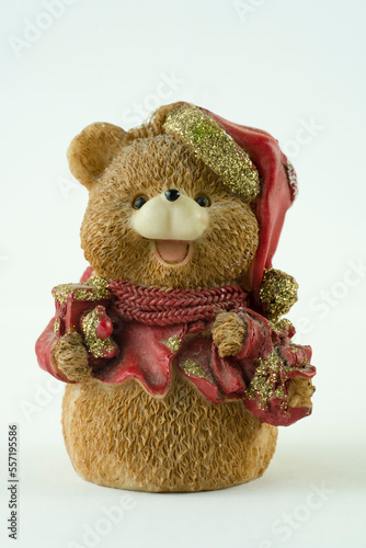 Cute bear figurine with gifts and Santa hat on white background