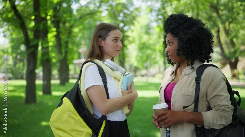 Two female friends meeting on campus, giving each other high fives, students Two female friends meeting on campus, giving each other high fives, students