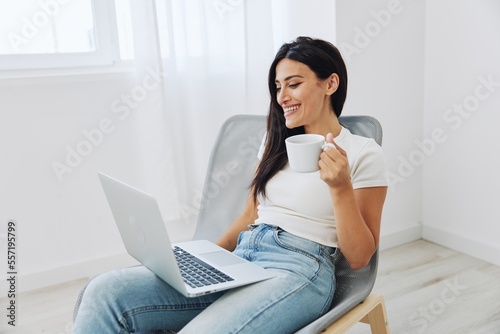 Woman relaxing at home sitting in a chair and watching a movie on her laptop with a cup of tea, happiness and laughter comedy, freelancer lifestyle © SHOTPRIME STUDIO