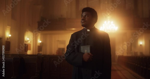 Portrait of a Young Black Priest Holding the Holy Bible in His Hand. A Servant of God Helping Lost Souls Find the Path of Righteousness through Faith. A Symbol Of Christianity, God's Love And Grace  photo