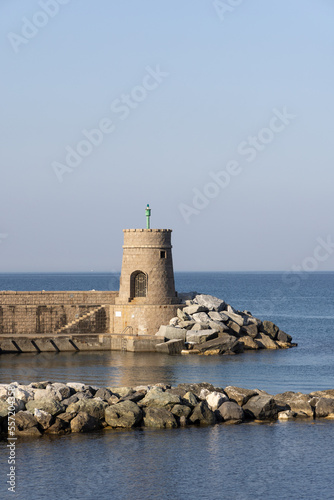 Old small lighthouse and stone wave breakers of Recco on a sunny summer day. Recco is a comune in the Metropolitan City of Genoa, region of Liguria, Italy.