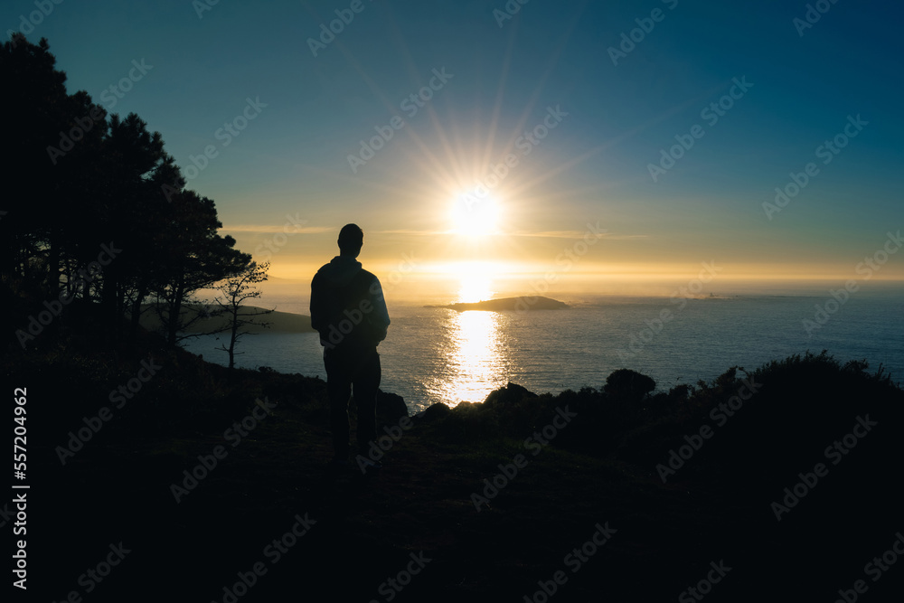 silhouette of a young woman on a cliff in Monteferro at sunset. Nigran - Spain