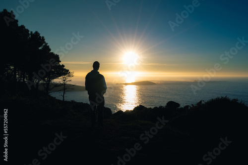 silhouette of a young woman on a cliff in Monteferro at sunset. Nigran - Spain