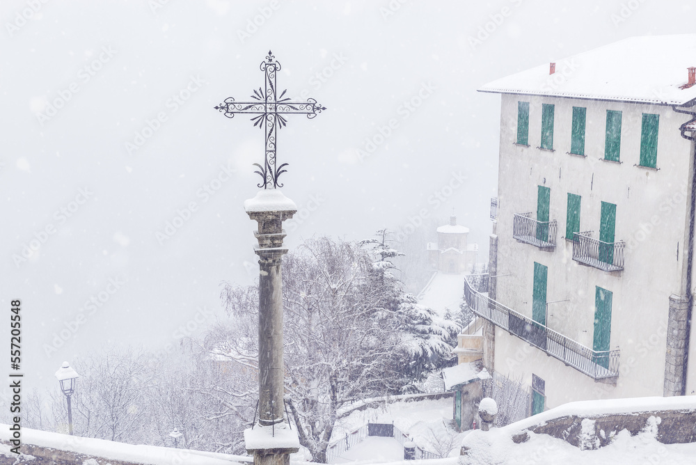 Obraz premium Fog and snowfall at the Sacro Monte di Varese (Santa Maria del Monte), Italy. Winter view downstream with the 14th chapel visible in the haze. World Heritage Site – Unesco