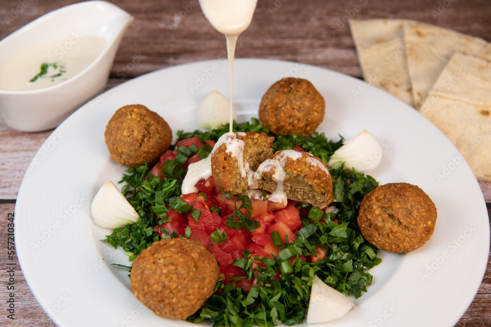 Vegetarian dish, falafel balls from spiced chickpeas with chopped parsley, fresh onions and tomato, tahini sauce, High quality photo