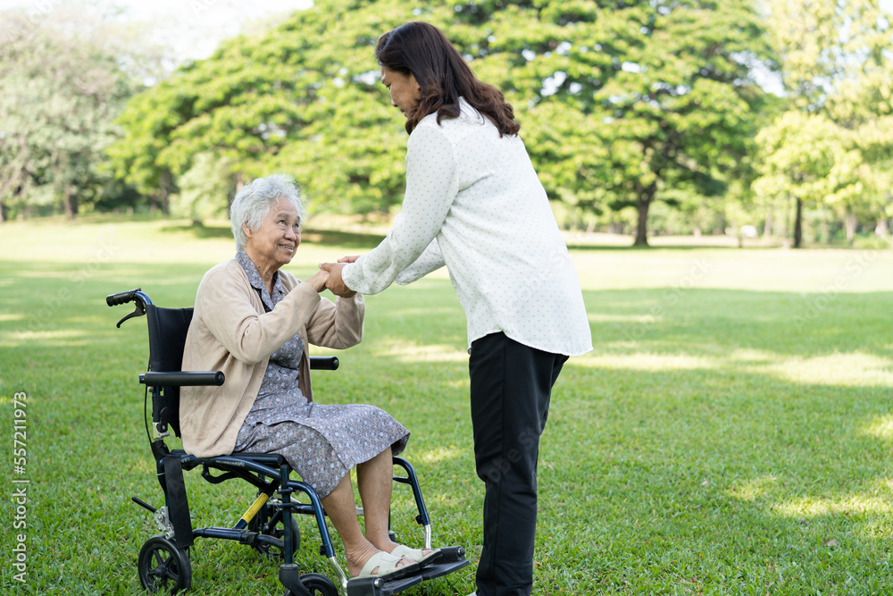 Fototapeta premium Caregiver help and care Asian senior or elderly old lady woman patient sitting on wheelchair in park, healthy strong medical concept.