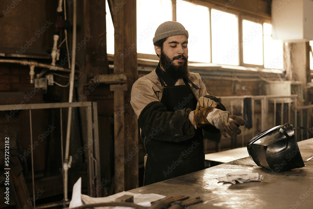 Man starting his work with putting on protective sleeves, apron and welding gloves Man starting his work with putting on protective sleeves, apron and welding gloves