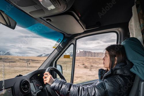 Female traveler drive camper van on empty mountainous road. New Zealand road trip adventure in converted camper van. 