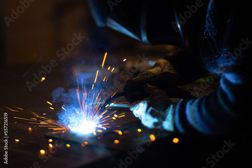 Metal welder works with a steel welder in a factory with protective equipment. Manufacture of metal structures and repair and construction services according to the concept of manual labor.