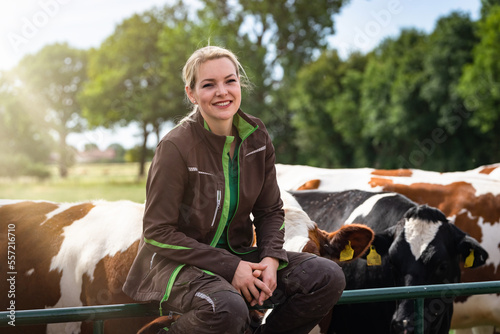 Obraz na płótnie Ausbildungsberuf Landwirtschaft - Auszubildende sitzt auf einem Weidetor einer Kuhweide