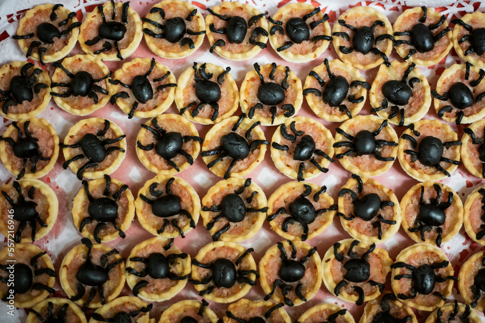 Spider shaped cookies with black olives on a pattern shelf