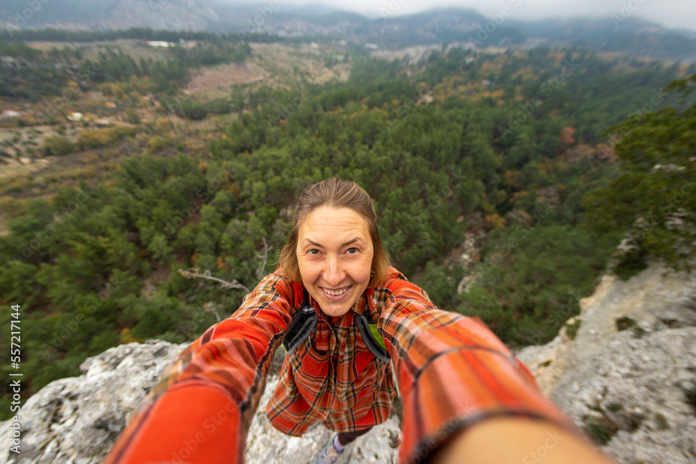 selfie of a woman on the background of a rocky and mountainous area.