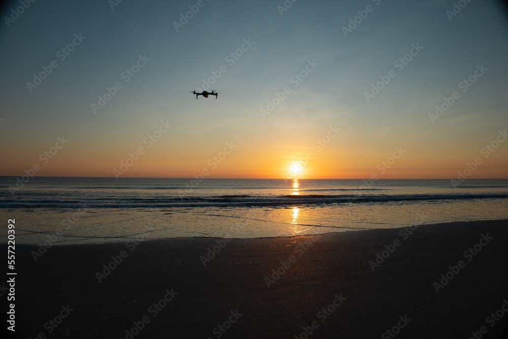 Drone facing the sunrise over the beach