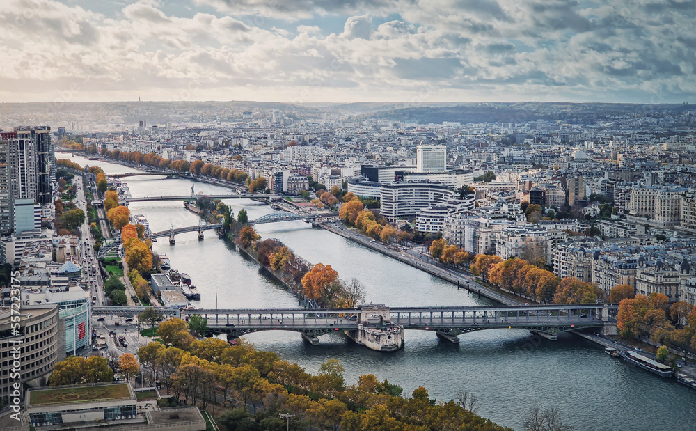 Aerial panorama of Paris city, France. Multiple bridges over the Seine river and vibrant colored autumn trees on the riverbank. Beautiful fall season cityscape panoramic view