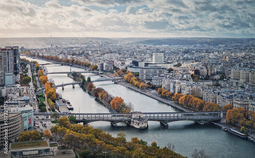 Aerial panorama of Paris city  France. Multiple bridges over the Seine river and vibrant colored autumn trees on the riverbank. Beautiful fall season cityscape panoramic view