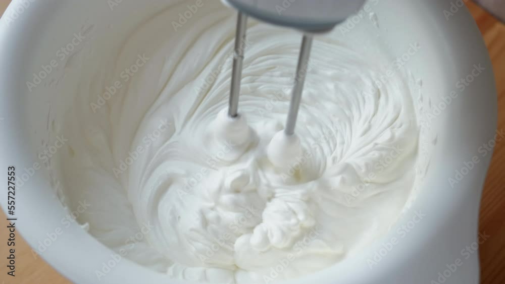 mixer whips cream. Whipping white cream with a mixer in slow motion mixer whips cream. Whipping white cream with a mixer in slow motion
