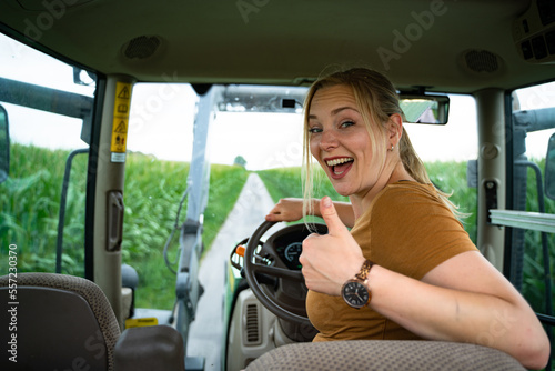 Daumen hoch, eine fröhliche Landwirtin am Steuers eines Traktors, Nahaufnahme.