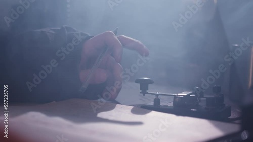 Employee communicates using telegraph and Morse code. Person taps with finger holding pen and writing down observations in diary closeup photo