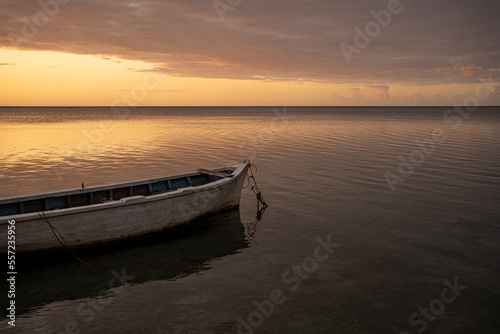 Baie-du-Tombeau Mauritius Sunset over the bay with single fishing boat sloop in foreground and horizon showing large scale fishing boards silhouetted in the background