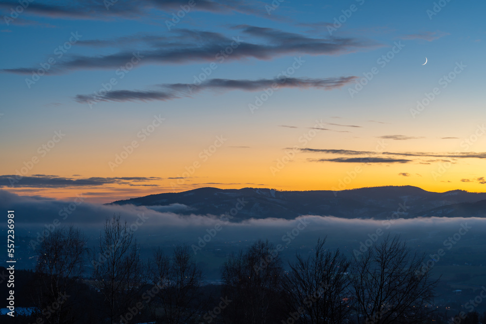 Winter sunset in Moravian-Silesian Beskids in Czech Republic nearby polish border, colorful sky and mountain peaks above the misty valley