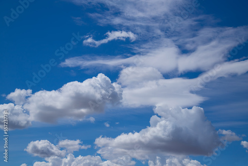 Sunny weather with cumulus and cirrus clouds on blue sky.