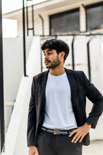 A bearded man doing a pose wearing white shirt with suit as the outer on the outdoor