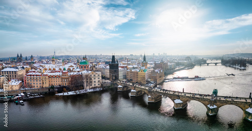 Panoramic aerial view of the snow covered skyline of Prague with Charles Bridge, old town and Vltava River during winter time
