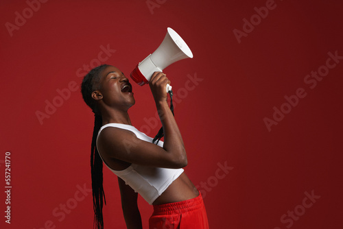 Ethnic woman with megaphone near red wall photo