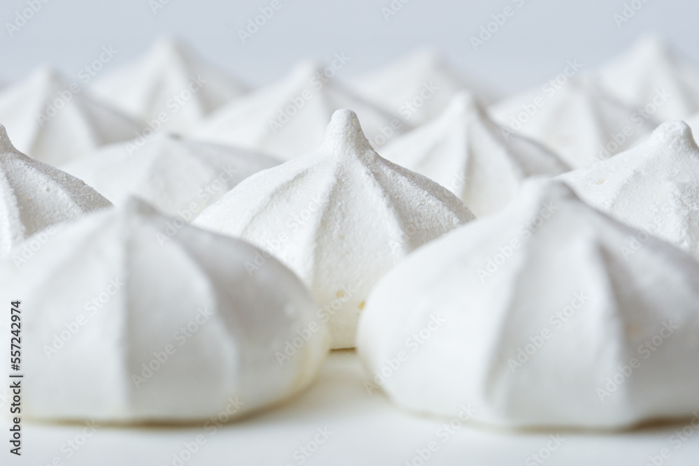 White meringues close-up on a white background, selective focus. White meringues close-up on a white background, selective focus.