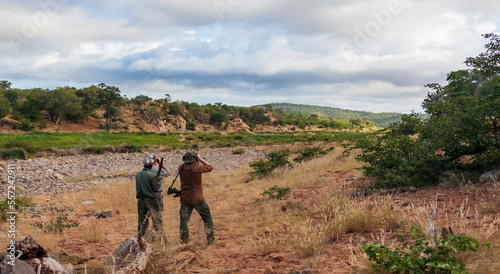  Hunter,  guide and tracker in the savannah are looking at animals in search of trophy. © okyela