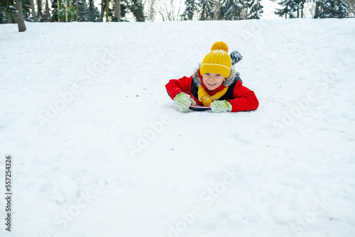 Boy sledding in winter forest. Winter holidays.