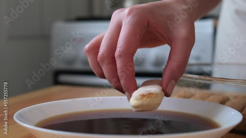 The process of cooking tiramisu. the cook dips savoiardi, savoyardi, adyfinger (biscuit), sponge fingers, boudoirs, baby fingers in coffee and spreads it on mascarpone photo