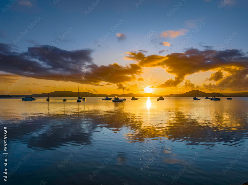 Aerial sunrise waterscape with boats, clouds and the sun