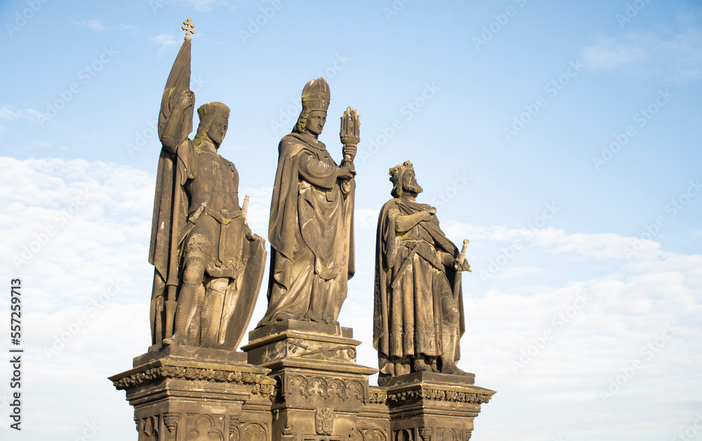 statue of three saints on charles bridge in prague from the front in blue sky day