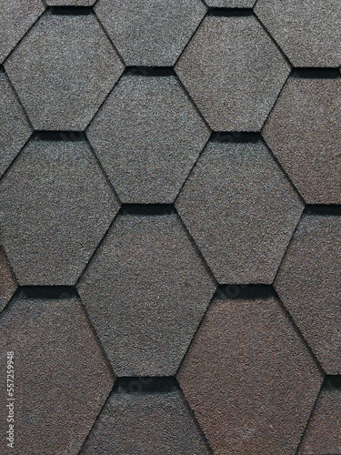 The roof is covered with hexagonal asphalt soft tiles. Abstract geometric background on the theme of modern architecture or construction industry.