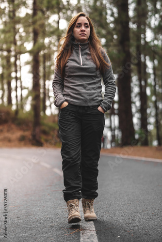caucasian girl walking along a road in the middle of the forest © YerayS