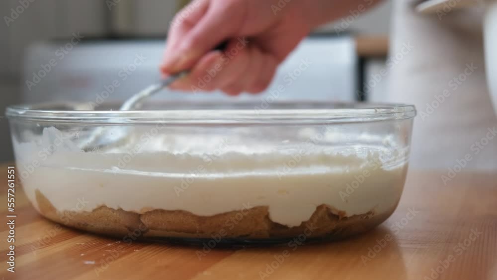 the process of cooking tiramisu. the cook lays out and smears