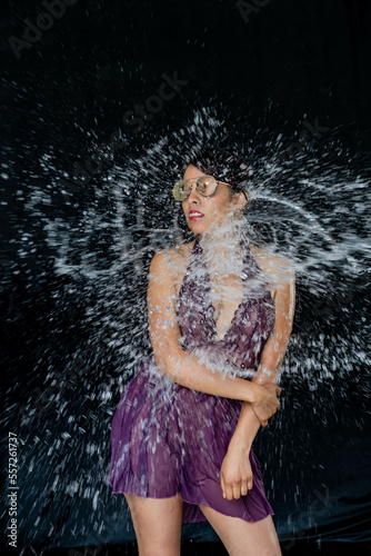 A Lovely Latin Bikini Model Poses In A Studio Environment While Water Is Thrown On Her