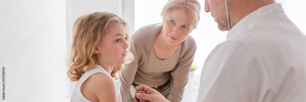 Pediatrician examining cute boy with pneumonia, worried mother b Pediatrician examining cute boy with pneumonia, worried mother b