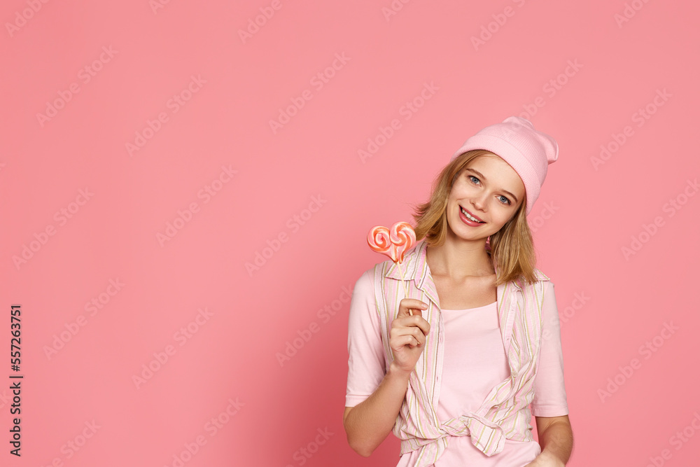 blonde woman holding candy on pink background.