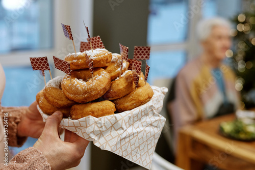 Close up shot of unrecognizable woman bringing tasty donuts decorated with food flags photo