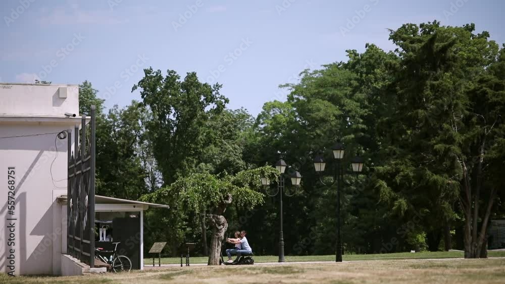 An electric motorcycle with a beautiful young couple of people rides through the summer green park. An electric motorcycle with a beautiful young couple of people rides through the summer green park.