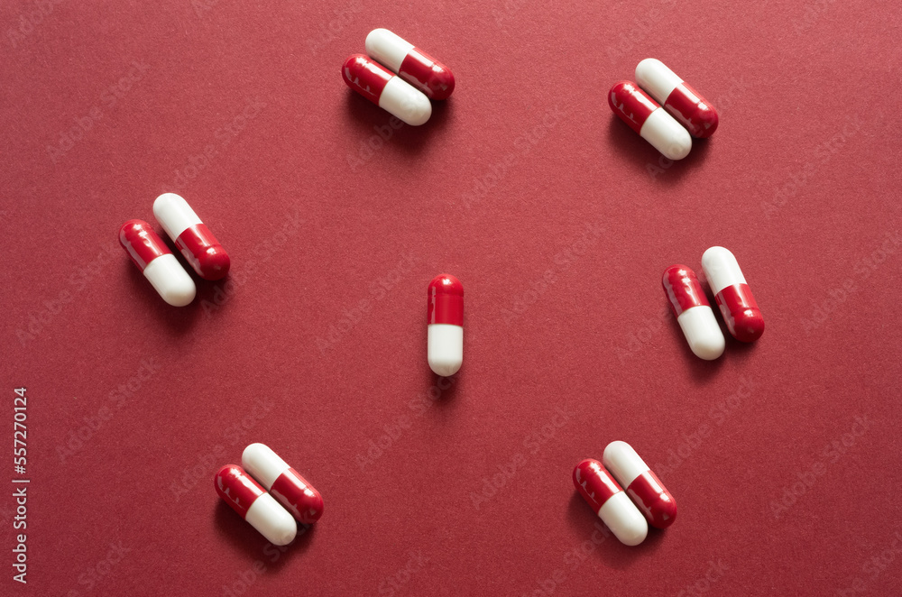 Medicines, pills. Medical background, red-white capsules on a red background. Top view of pills on red surface Medicines, pills. Medical background, red-white capsules on a red background. Top view of pills on red surface