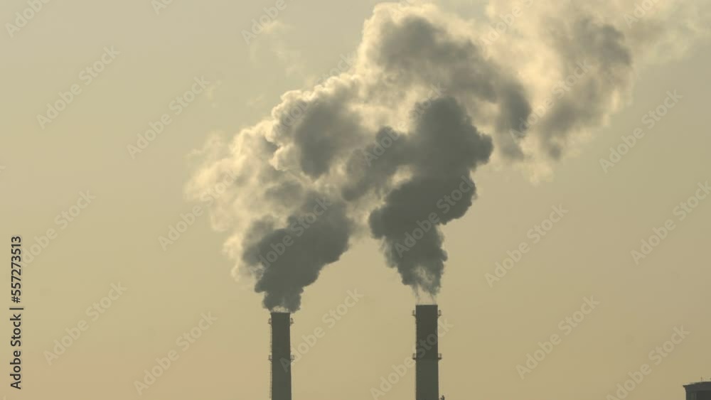 Smoke from chimneys. Top of two thin tubes next to each other. Close-up. Pipes in silhouette. Smoke from chimneys. Top of two thin tubes next to each other. Close-up. Pipes in silhouette.